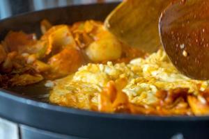 tokboki koreanisches traditionelles essen heißer und würziger reiskuchen, kombination und puff mit käse und gemüse auf dem schwarzen tisch auftragen foto