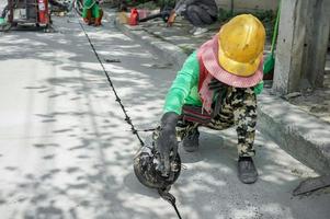 arbeiter lassen asphaltflüssigkeit in das loch der straße fallen. foto