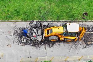 Arbeiter und Traktor entfernen Asphalt foto