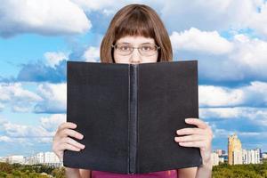 Mädchen liest großes Buch und blaue Wolken über der Stadt foto