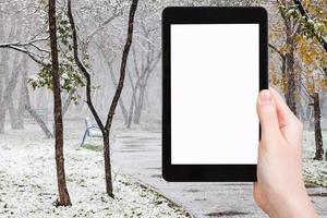 Tablet-PC und erster Schneefall im öffentlichen Garten foto