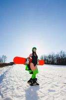 junge schöne Frau posiert mit einem Snowboard auf einer Skipiste foto