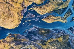 abstraktes Muster blauer Gletscherflüsse, das im Sommer durch vulkanisches Moosfeld im isländischen Hochland fließt foto