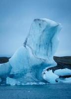 blauer eisberg, der auf gletscherlagune vom breioamerkurjokull-gletscher in jokulsarlon, island schwimmt foto