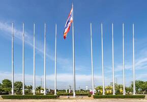 thailändische flagge an den stangen mit blauer himmelwolke und baum auf der rückseite. foto