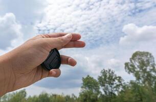 Die linke Hand hält einen runden Kunststoffhalter in den Himmel mit dem blauen Himmel und den sensiblen Fokus der Bäume foto