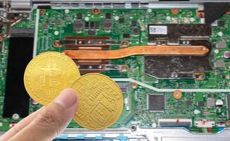 Bitcoin in der Hand mit Motherboard unscharfem Hintergrund halten. foto