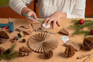 Mädchen macht Christbaumschmuck aus Papier mit ihren eigenen Händen. Schritt 1. Schritt-für-Schritt-Anleitung foto