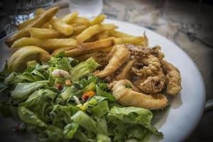 ein Gericht aus gebratenen Calamari und grünem Salat foto