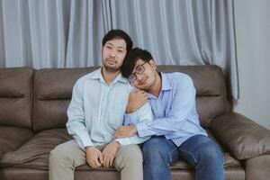 asiatisches homosexuelles männliches lgbt-paar, junger asiatischer schwuler mann, der vor glück hände hält, während er im wohnzimmer sitzt, homosexuelles und lgbt-lifestyle-konzept foto