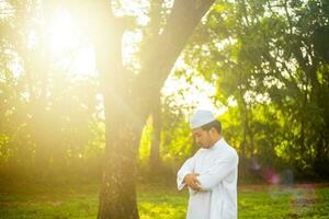 junger asiatischer muslimischer mann, der bei sonnenaufgang betet, ramadan-festkonzept foto