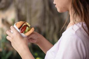 junge Frau, die sich darauf vorbereitet, einen großen Burger zu beißen foto