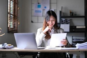 schöne junge asiatische frau, die mit laptop im café sitzt. glückliche junge Geschäftsfrau, die am Tisch im Café mit Tab-Top-Computer sitzt. foto