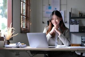 schöne junge asiatische frau, die mit laptop im café sitzt. glückliche junge Geschäftsfrau, die am Tisch im Café mit Tab-Top-Computer sitzt. foto