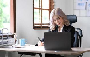 schöne junge asiatische frau, die mit laptop im café sitzt. glückliche junge Geschäftsfrau, die am Tisch im Café mit Tab-Top-Computer sitzt. foto