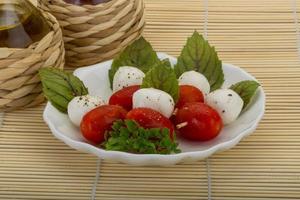 Caprese-Salat auf dem Teller und Holzhintergrund foto