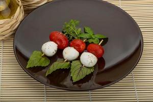 Caprese-Salat auf dem Teller und Holzhintergrund foto