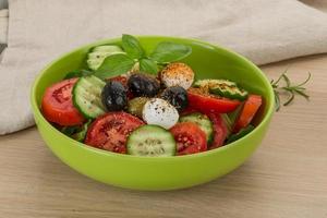 Salat mit Mozzarella und Tomaten in einer Schüssel auf Holzhintergrund foto