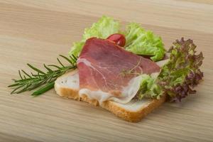 Prosciutto-Sandwich auf Holzbrett und Holzhintergrund foto