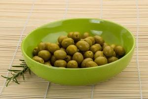 grüne Oliven in einer Schüssel auf hölzernem Hintergrund foto