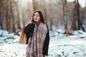 junges schönes Modell, das im Winterwald aufwirft. stilvolles Modeporträt foto