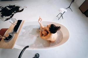 entspannte dame, die ein bad nimmt, in der badewanne genießt und sich entspannt foto