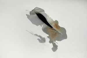 Loch im Metall. beschädigter Stahl mit weißer Farbe. gebrochene Oberfläche des Autos. foto