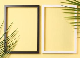 sommerkonzept - zwei fotorahmen und palmblätter auf pastellgelbem hintergrund foto