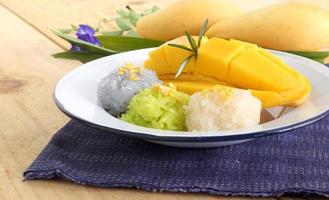 thailändisches berühmtes köstliches dessert - nahaufnahmeteller mit süßer frischer reifer mango mit dreifarbigem klebrigem reis, grün von pandan und lila von der schmetterlingserbsenblume foto