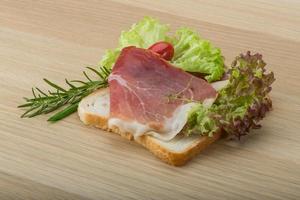 Prosciutto-Sandwich auf Holzbrett und Holzhintergrund foto