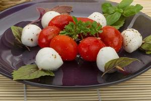 Caprese-Salat auf dem Teller und Holzhintergrund foto