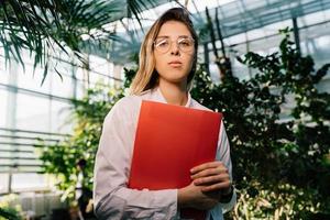 Junger Agraringenieur, der im Gewächshaus arbeitet. junge wissenschaftlerin, die in die kamera schaut foto