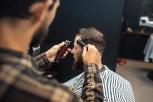 meister im friseursalon macht männerhaarschnitt mit haarschneidemaschine foto