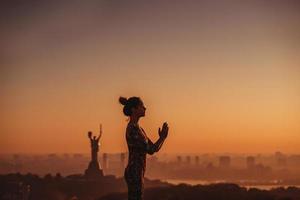 Frau beim Yoga auf dem Dach eines Wolkenkratzers in der Großstadt. foto