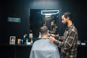 meister im friseursalon macht männerhaarschnitt mit haarschneidemaschine foto