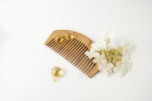 natürliches Öl Vitamine goldene Kapseln für Haare, die auf einem Holzkamm liegen foto