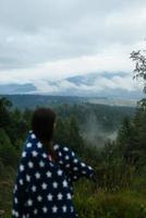 Frau, die auf einem Hügel steht, vor dem Hintergrund eines Tals foto