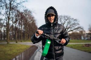 Frau in einer Jacke auf einem Elektroroller in einem Herbstpark. foto