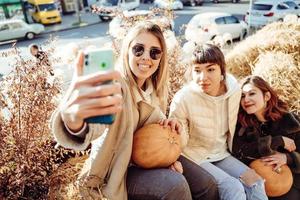 Schöne Mädchen, die auf Heuhaufen sitzen, machen ein Selfie foto