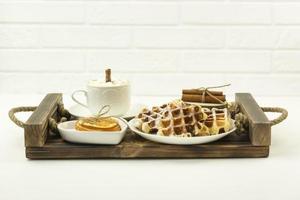 früher frühstückskaffee mit marshmallows und einer zimtstange und belgischen waffeln liegen auf einem holztablett foto