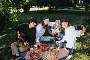 Gesellschaft von schönen jungen Leuten und Hunden, die ein Mittagessen im Freien haben. foto