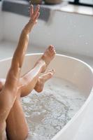 beschnittene Ansicht einer jungen Frau, die in einem schaumigen Bad liegt foto