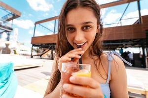 hübsche Frau im Bikini trinkt Cocktail auf der Poolparty. foto