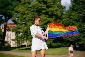 junge frau, die lgbt-stolzfahne im park schwenkt. foto