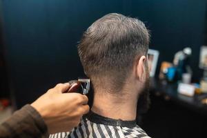 meister im friseursalon macht männerhaarschnitt mit haarschneidemaschine foto