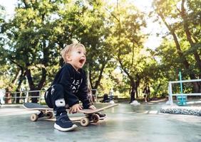 junges Kind, das im Park auf einem Skateboard sitzt. foto