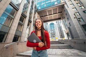 junge schöne Frau mit einem Laptop auf der Straße foto