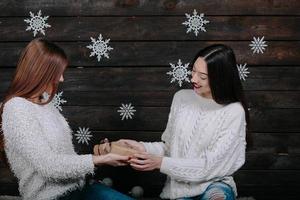 Zwei schöne Mädchen packen zusammen Geschenke aus foto