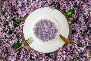 Servierplatte mit lila lila Blumen mit Gabel und Messer, Ansicht von oben. frisches frühlingskonzept. foto