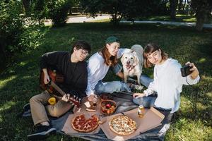 Gesellschaft von schönen jungen Leuten und Hunden, die ein Mittagessen im Freien haben. foto